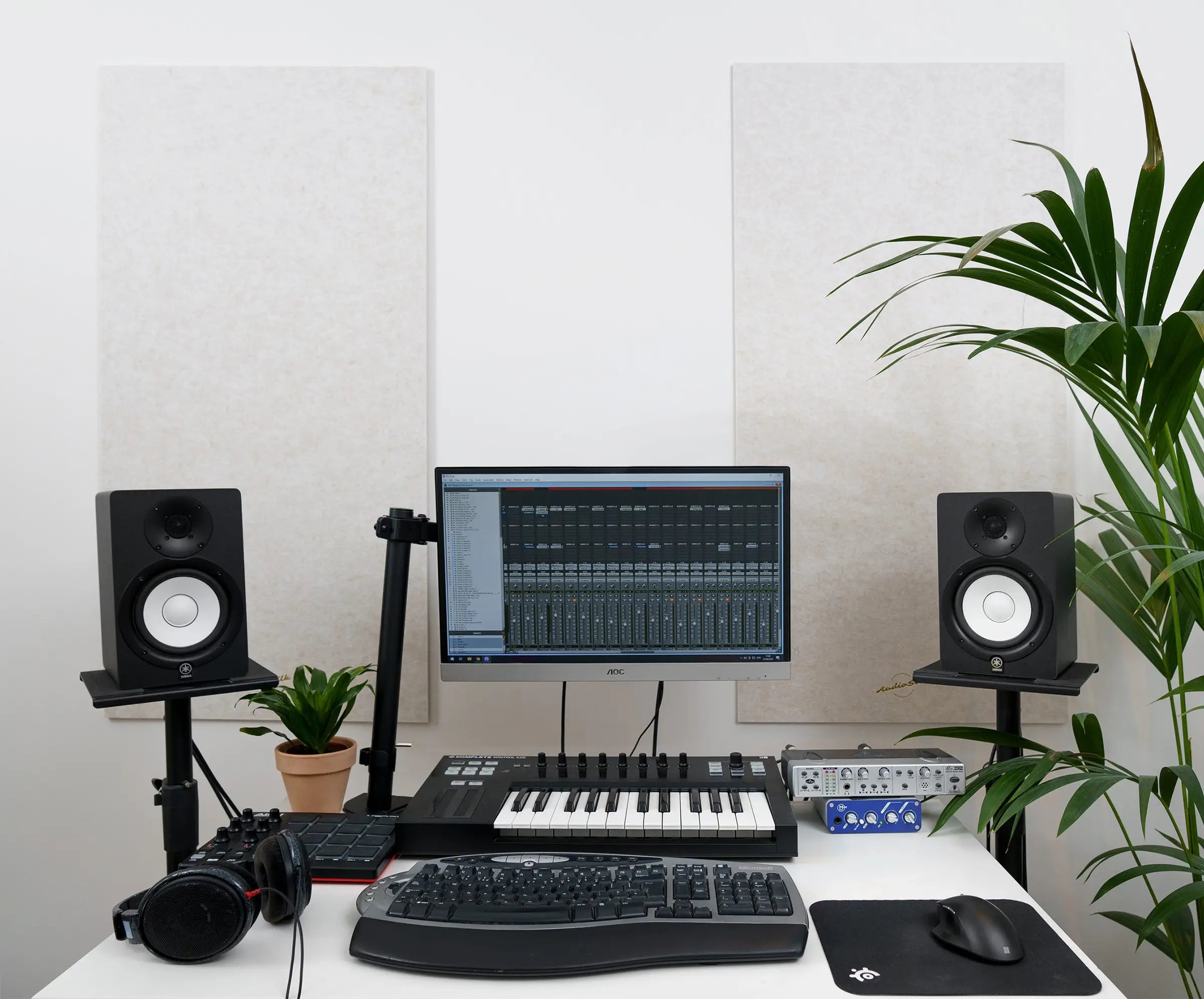 Two natural coloured AudioSilk panels hang on the wall of a bedroom studio with a computer and interface equipment on the desk